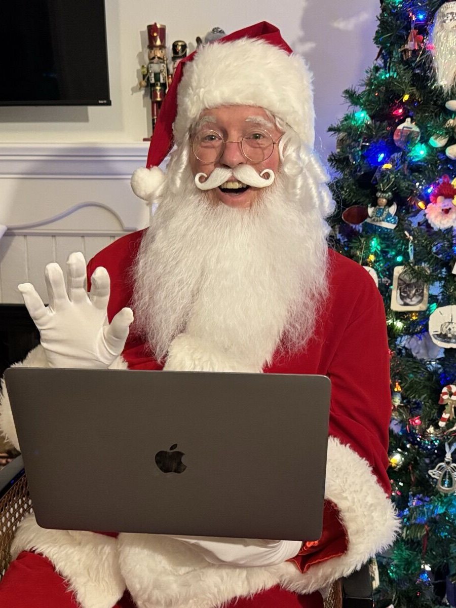 Smiling Santa in a velvet suit recording a personal video message